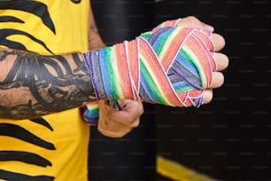 a man with a tattoo on his arm holding a multicolored wristband