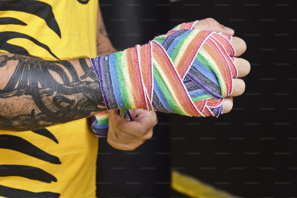 um homem com uma tatuagem no braço segurando uma pulseira multicolorida