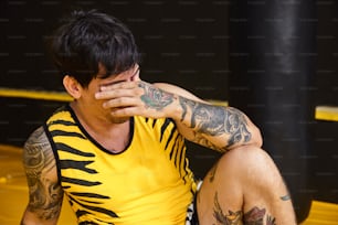 a man with tattoos covering his face sitting on a boxing ring