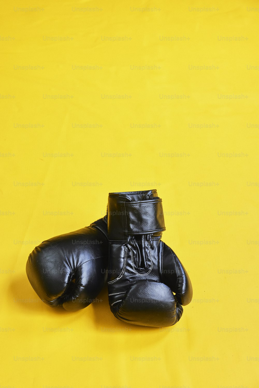 ein Paar schwarze Boxhandschuhe auf gelbem Hintergrund