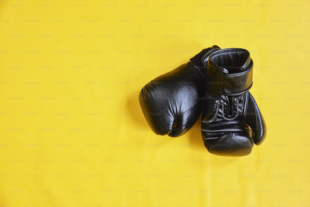 ein Paar schwarze Boxhandschuhe auf gelbem Hintergrund