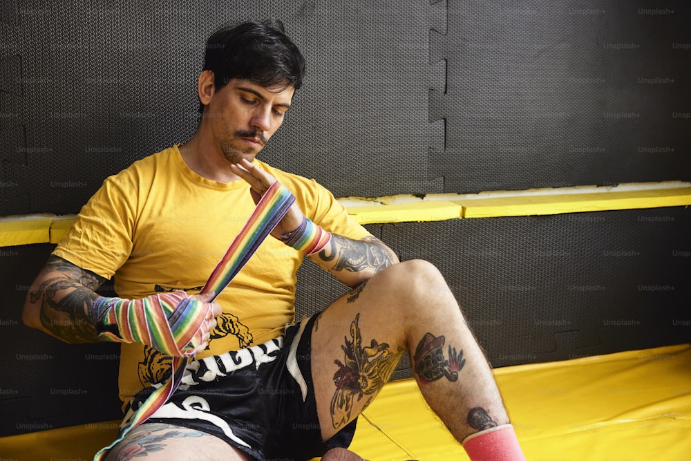 Un hombre sentado en un trampolín con tatuajes en las piernas