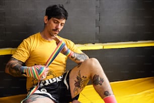 a man sitting on a trampoline with tattoos on his legs