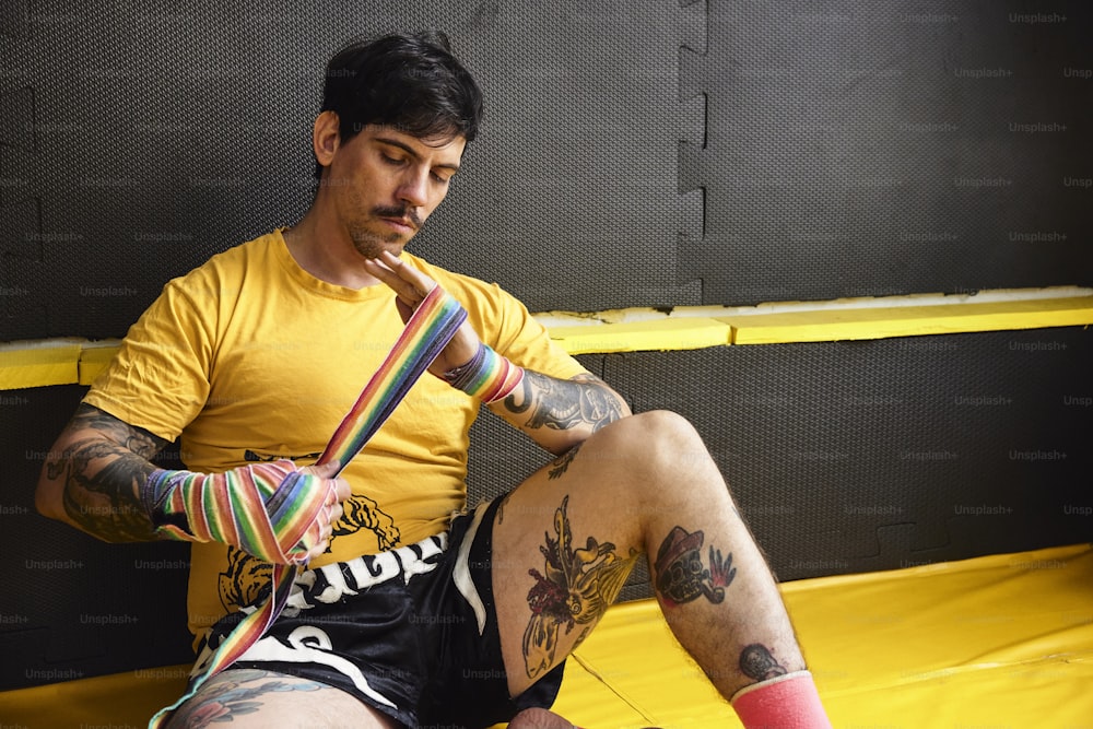 a man sitting on a trampoline with tattoos on his legs