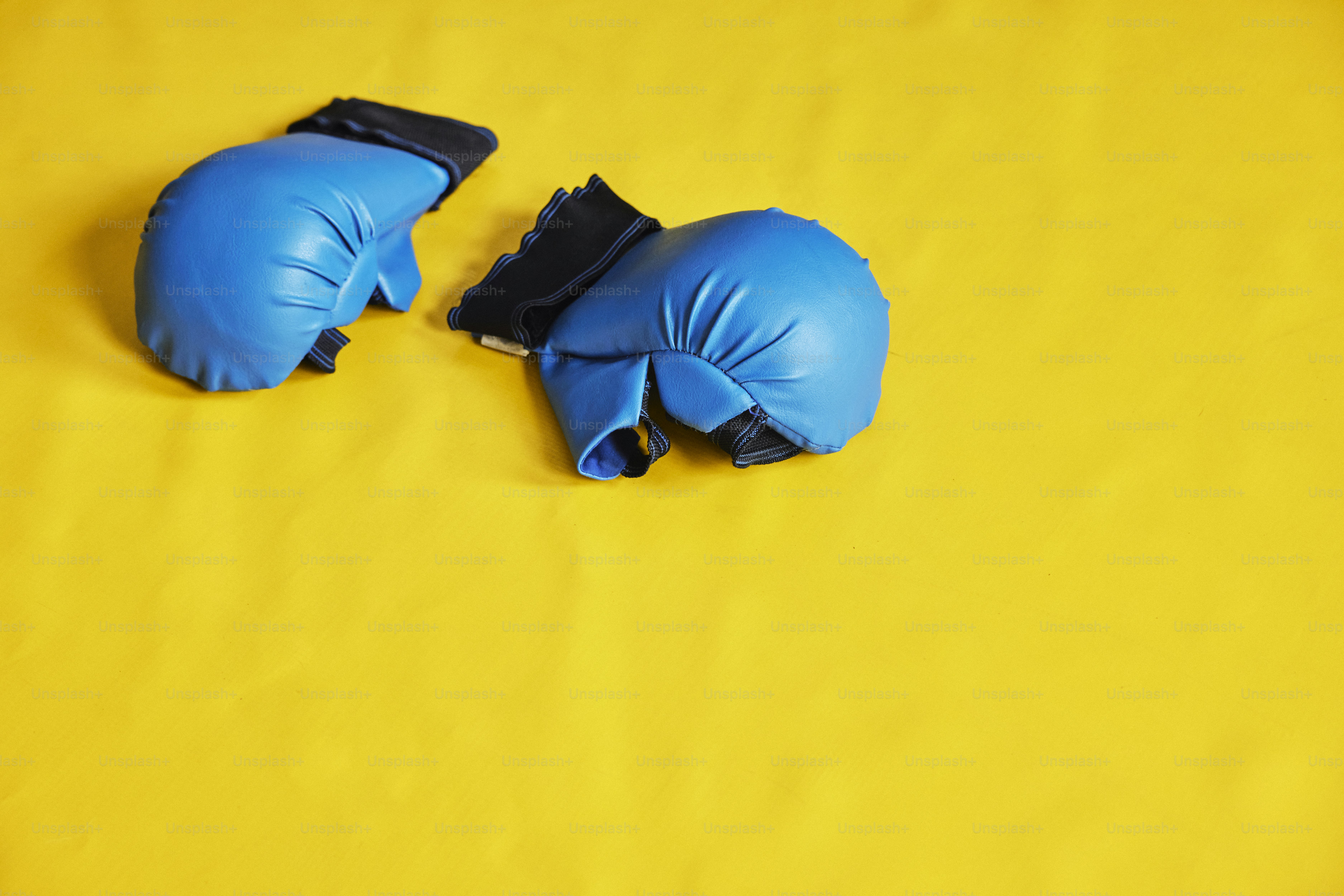 um par de luvas de boxe azuis em um fundo amarelo