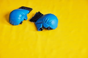 a pair of blue boxing gloves on a yellow background