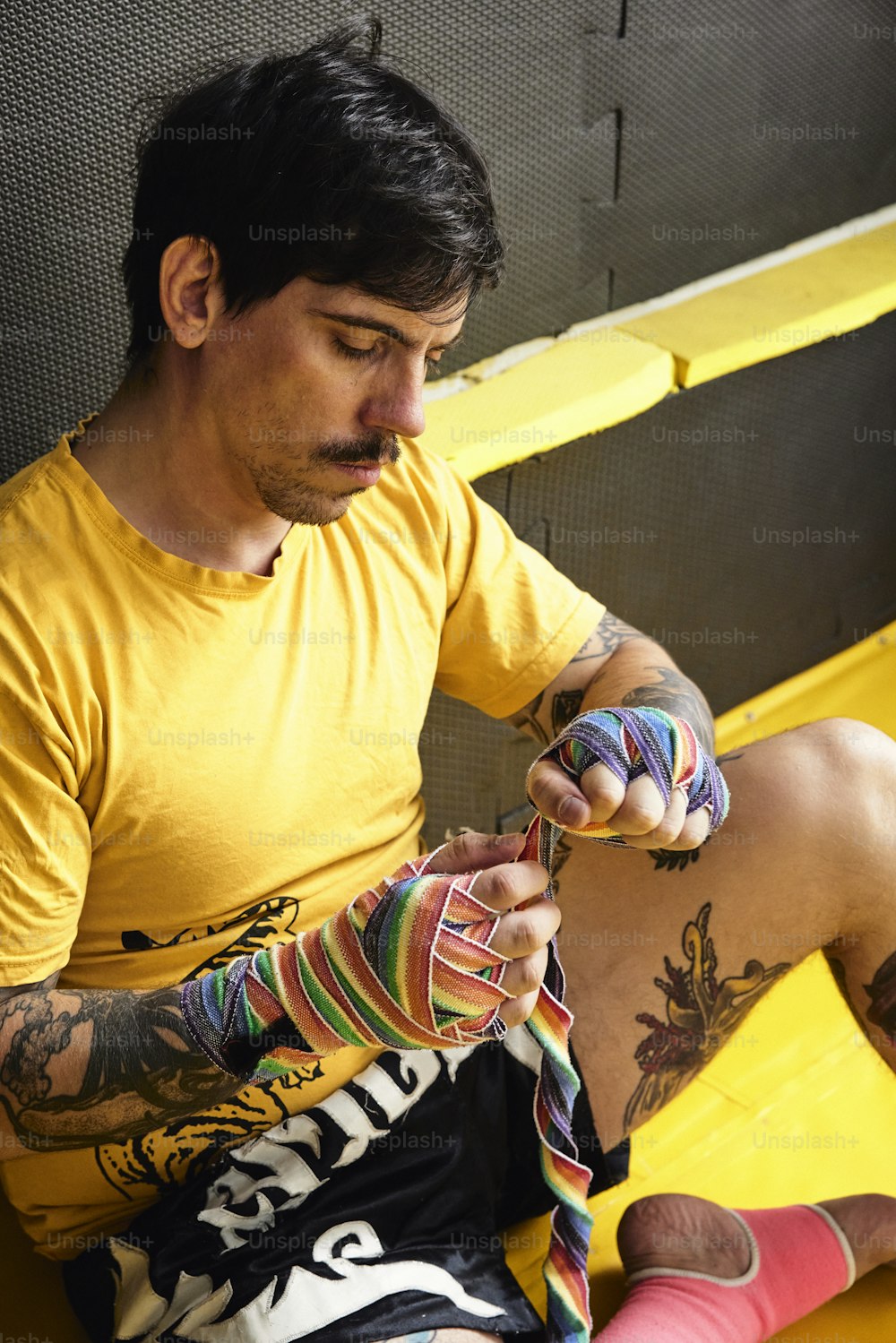 Un hombre sentado en un banco amarillo sosteniendo un par de calcetines de colores