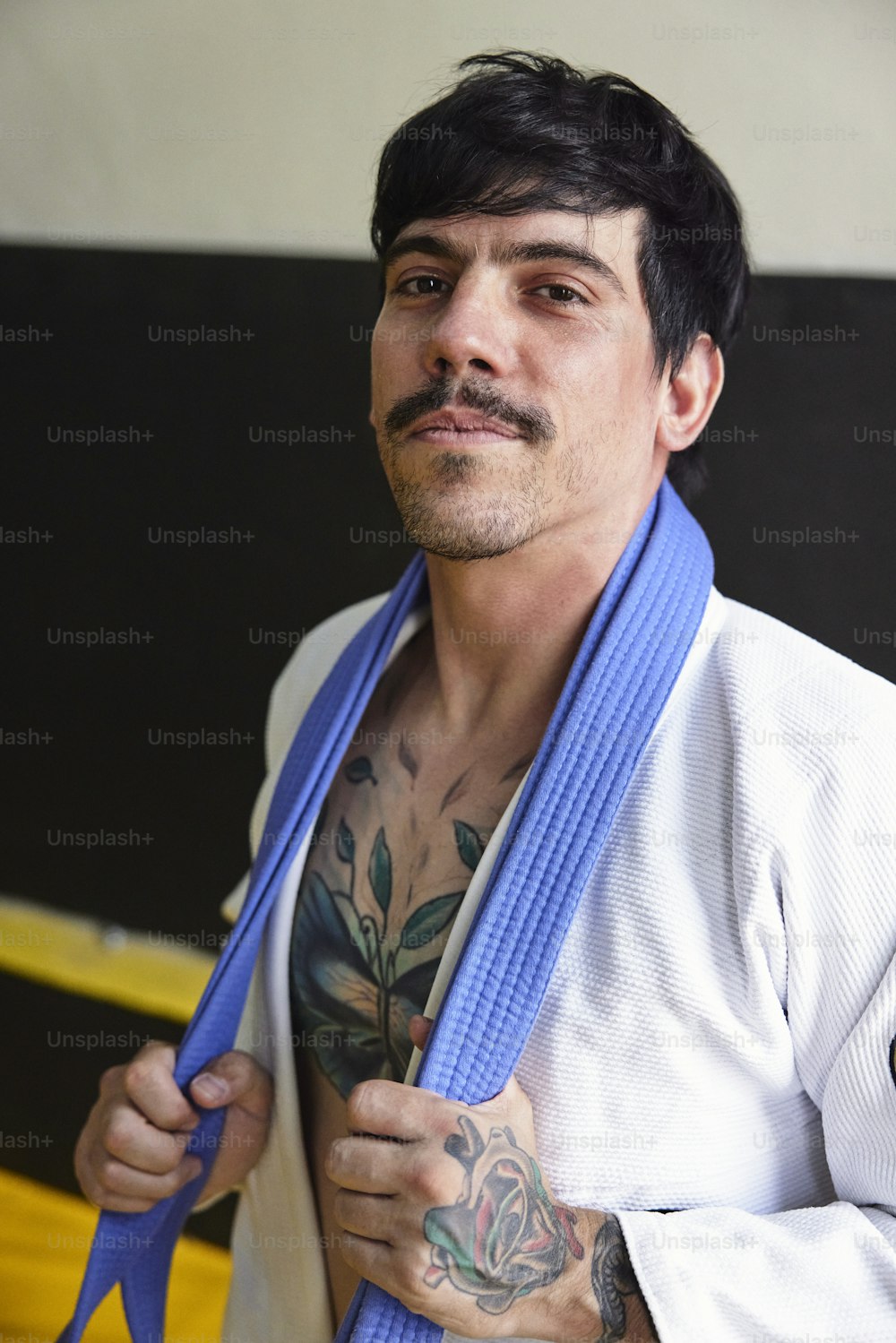 a man with a tattoo on his arm and a blue belt around his neck