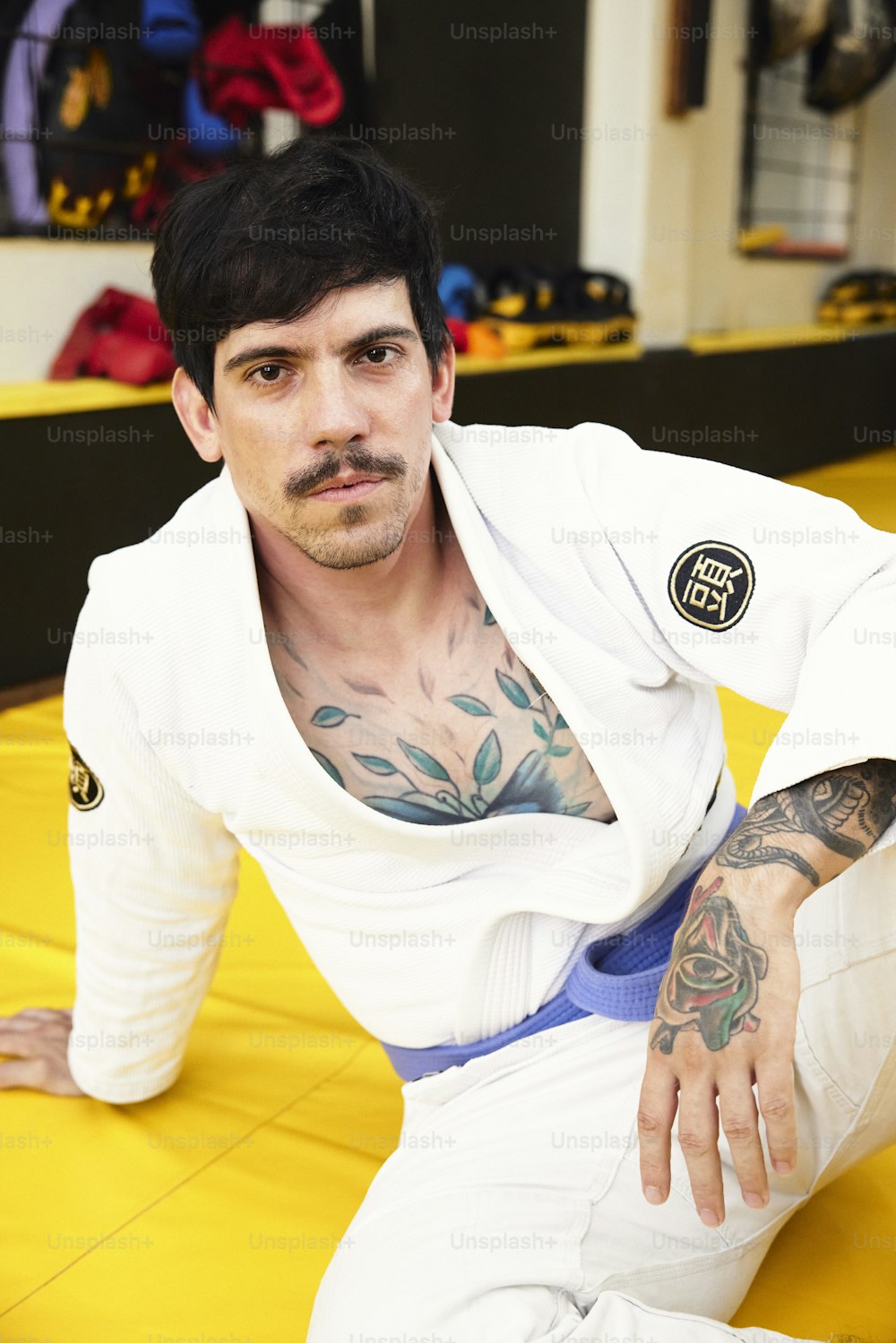 a man with tattoos sitting on a yellow mat