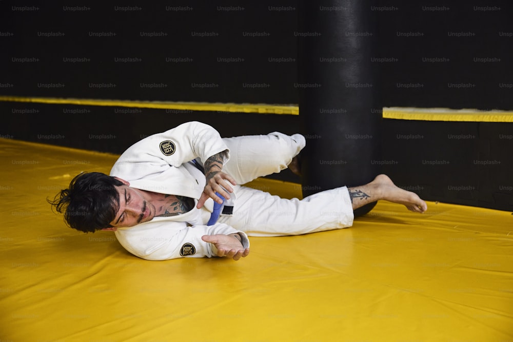 a man in a white suit is on a yellow mat