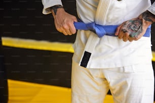 a man with a tattoo on his arm holding a blue belt