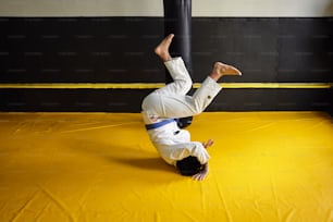 a man doing a handstand on a yellow mat
