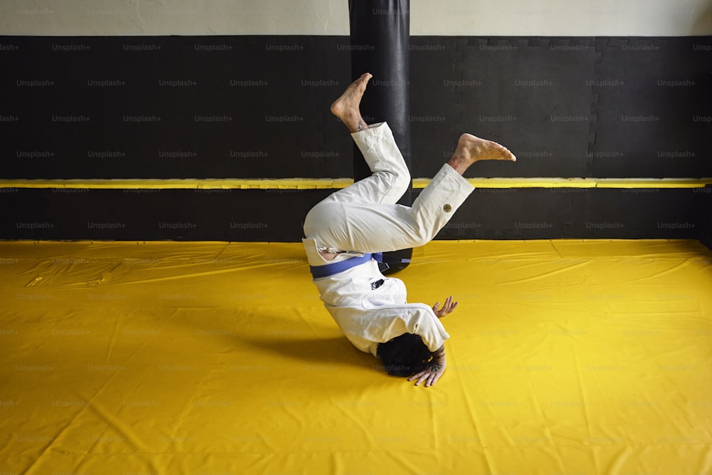 a man doing a handstand on a yellow mat