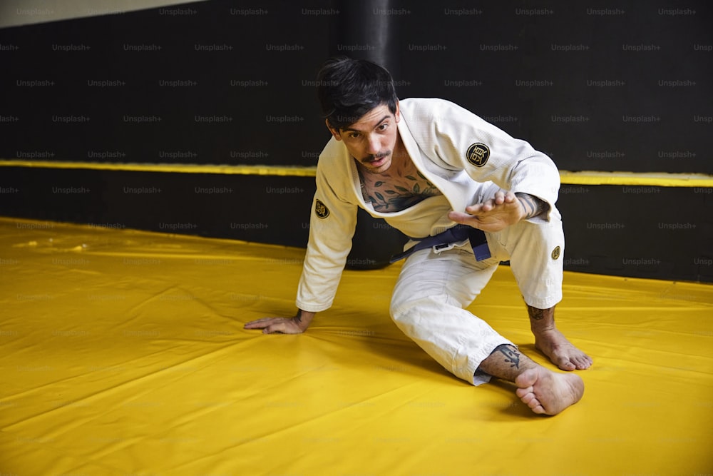 a man on a yellow mat with a black belt
