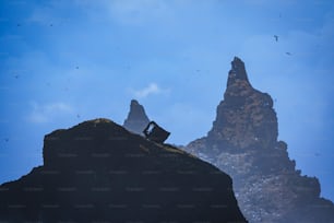 um homem sentado no topo de uma grande rocha ao lado de uma montanha
