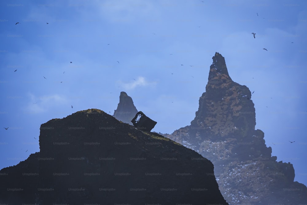 Ein Mann sitzt auf einem großen Felsen neben einem Berg