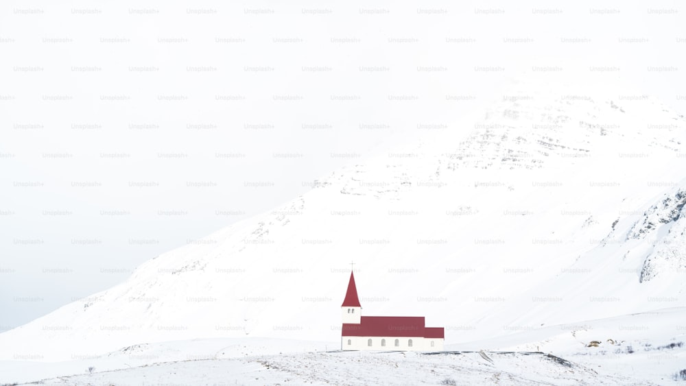 uma igreja vermelha e branca no meio de uma montanha nevada