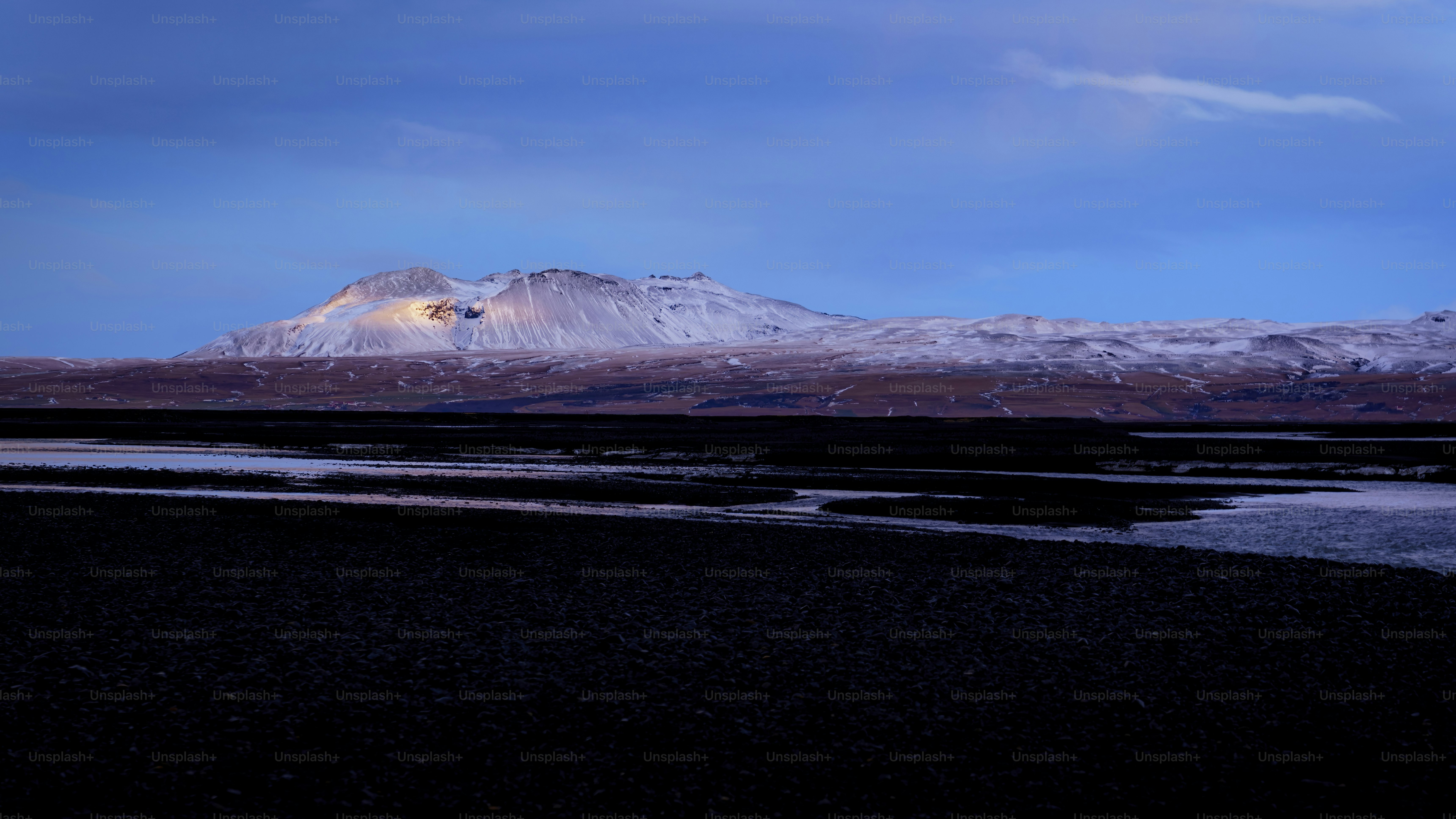 a snow covered mountain with a body of water in the foreground