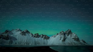 Eine schneebedeckte Bergkette mit grünem Licht am Himmel