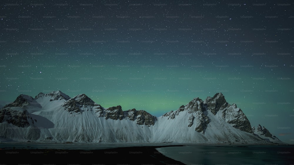 a snowy mountain range with a green light in the sky