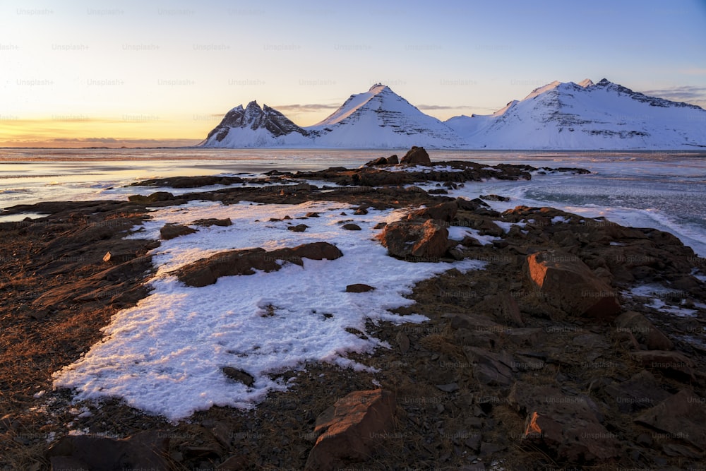 a snow covered beach with mountains in the background