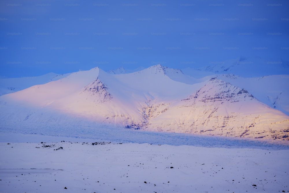 a snow covered mountain range under a blue sky