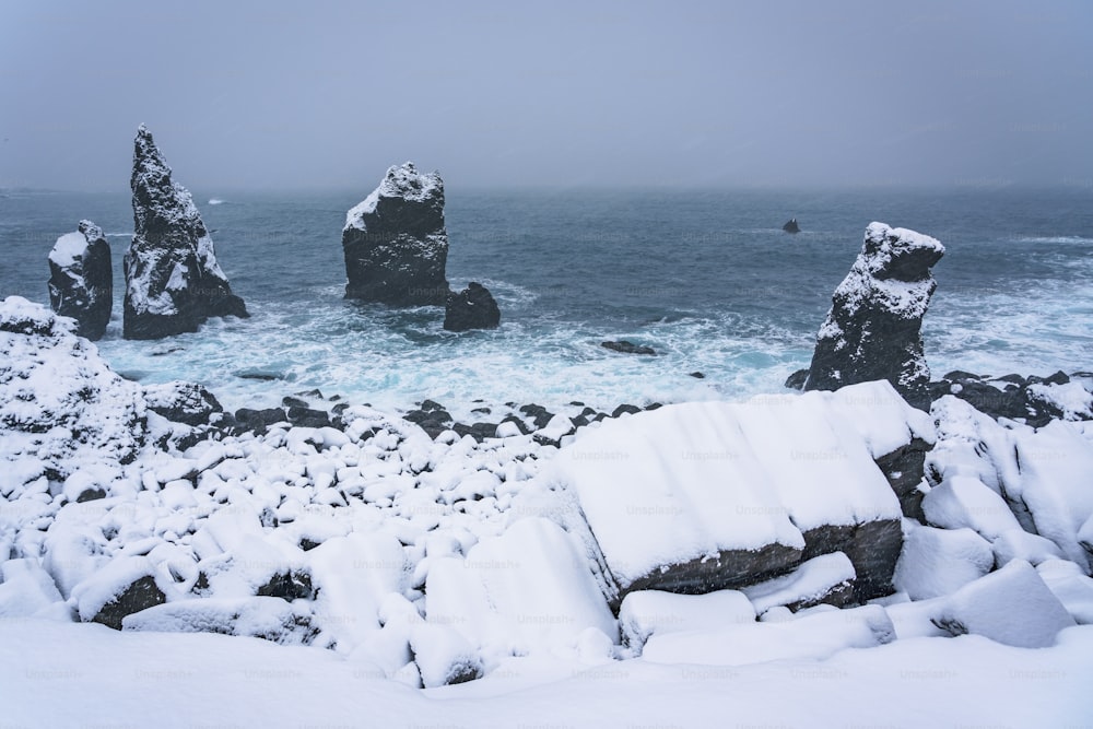 a rocky beach covered in snow next to the ocean