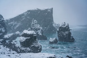 a large rock formation in the middle of a body of water covered in snow