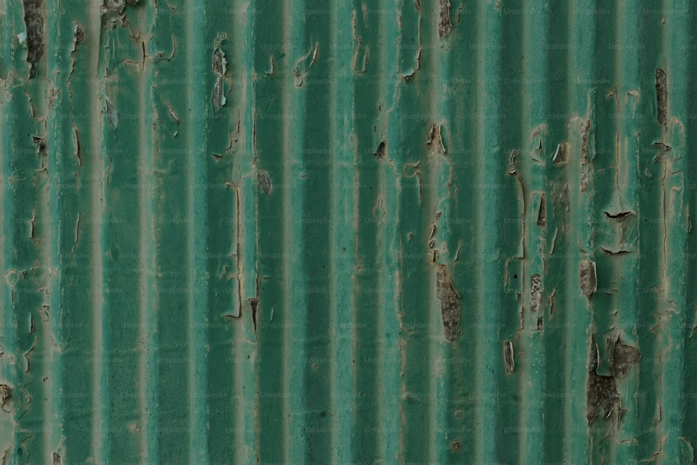 Un primer plano de una pared de metal verde con pintura descascarada