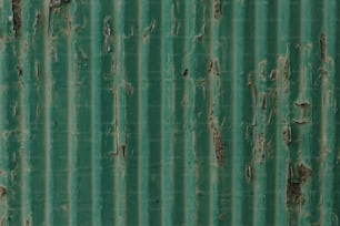 Un primer plano de una pared de metal verde con pintura descascarada