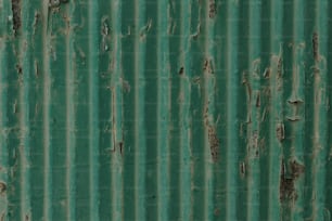 a close up of a green metal wall with peeling paint