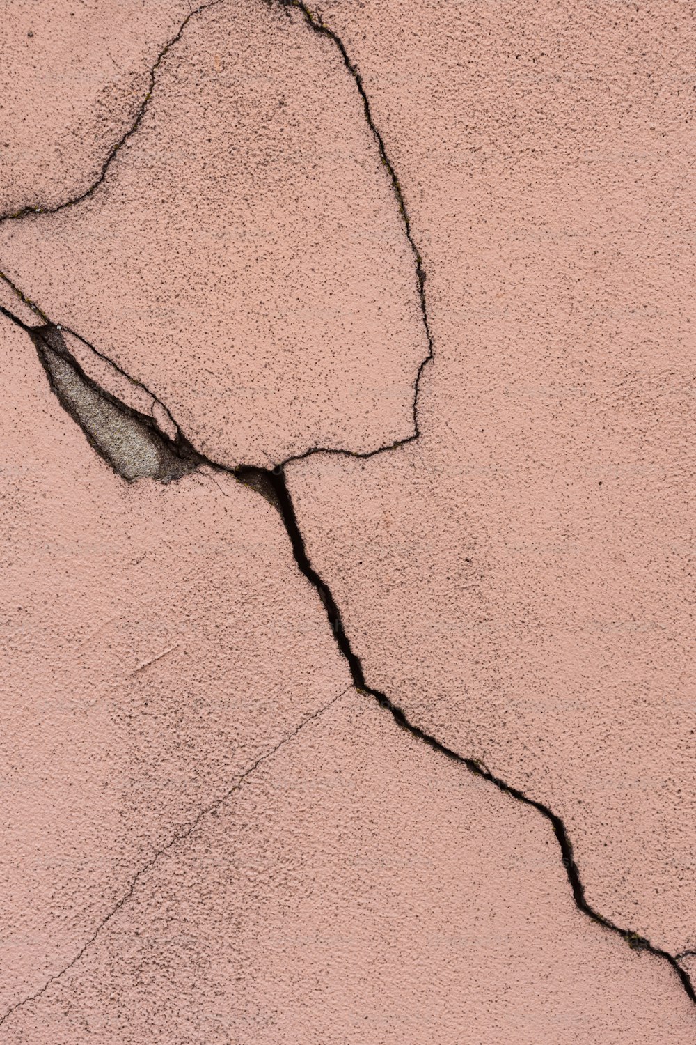 a crack in the side of a pink wall