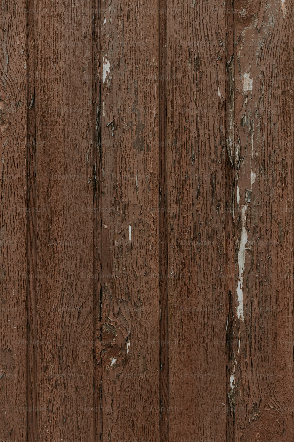 una parete di legno marrone con vernice scrostata su di esso