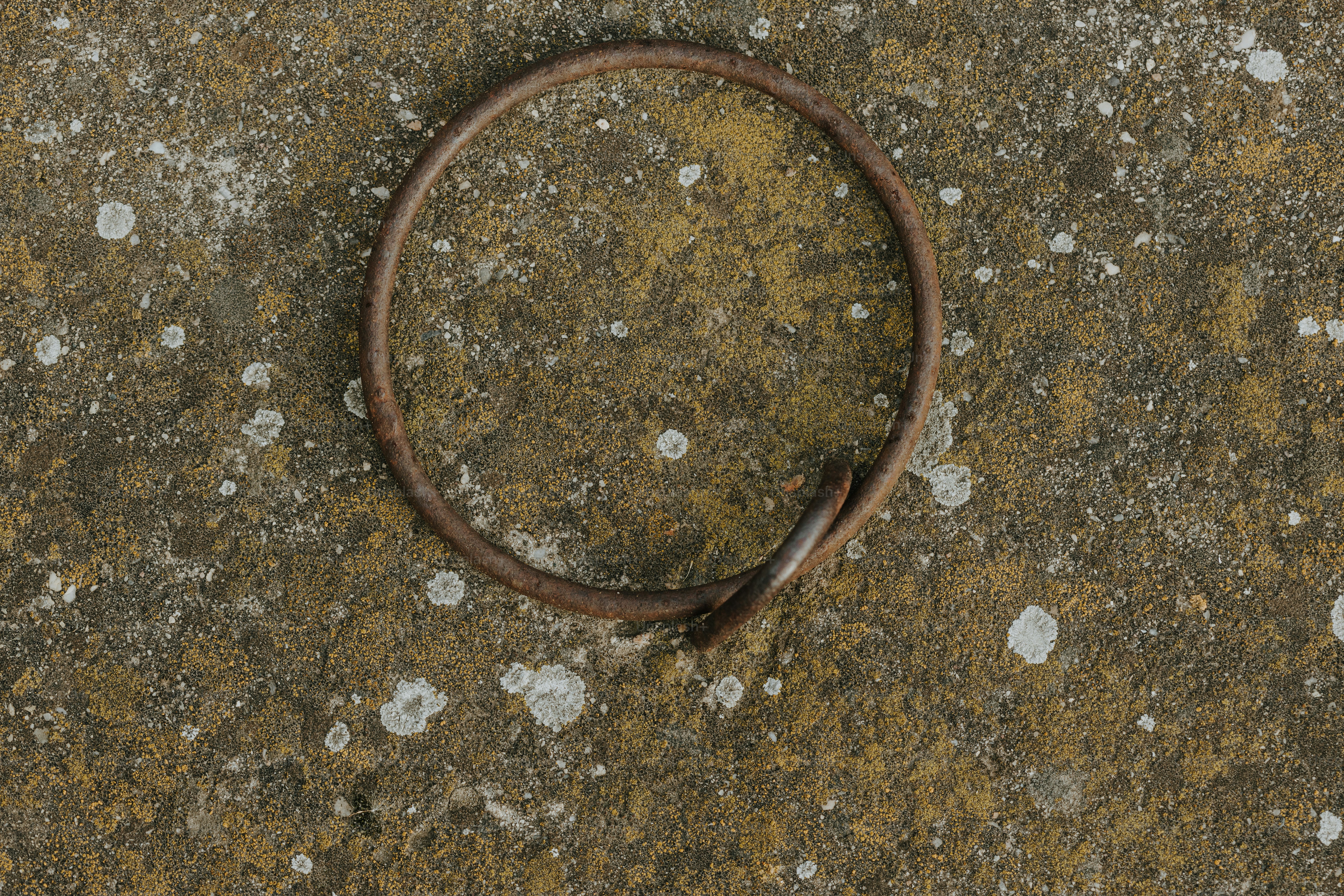 a rusted metal ring sitting on top of a cement ground