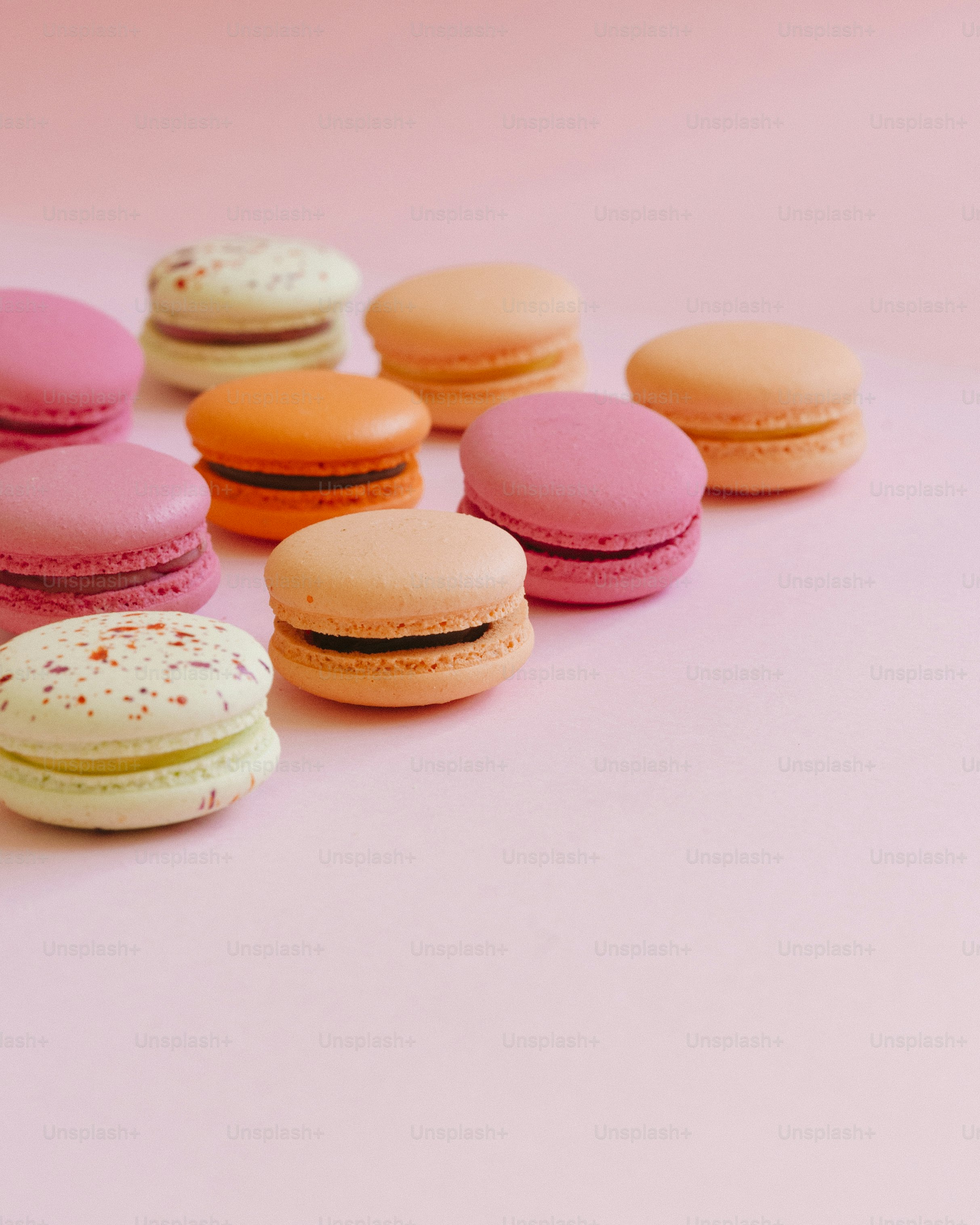 a group of macaroons sitting on top of a pink surface