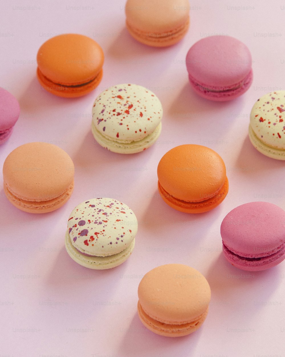 a group of macaroons sitting on top of a pink surface