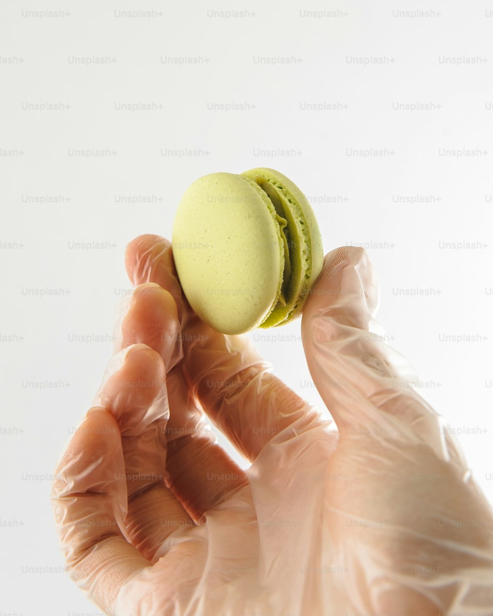 Eine Hand in einem weißen Handschuh mit einem grünen Makkaroni-Käse-Sandwich