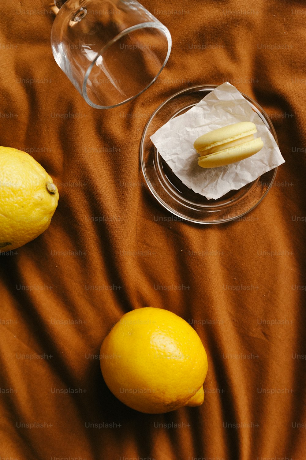 two lemons and a glass of water on a bed