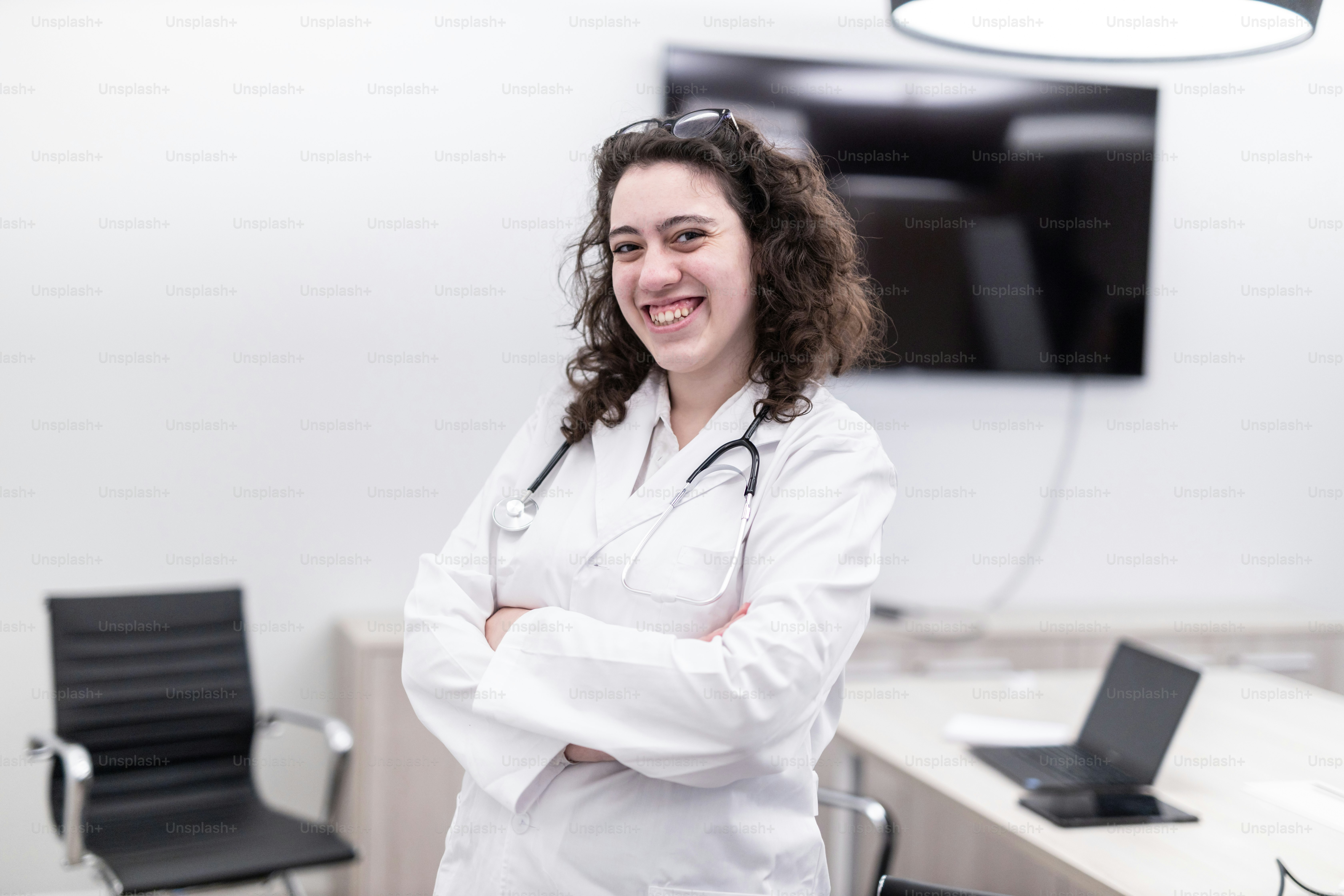 Una mujer con una bata blanca de laboratorio de pie con los brazos cruzados