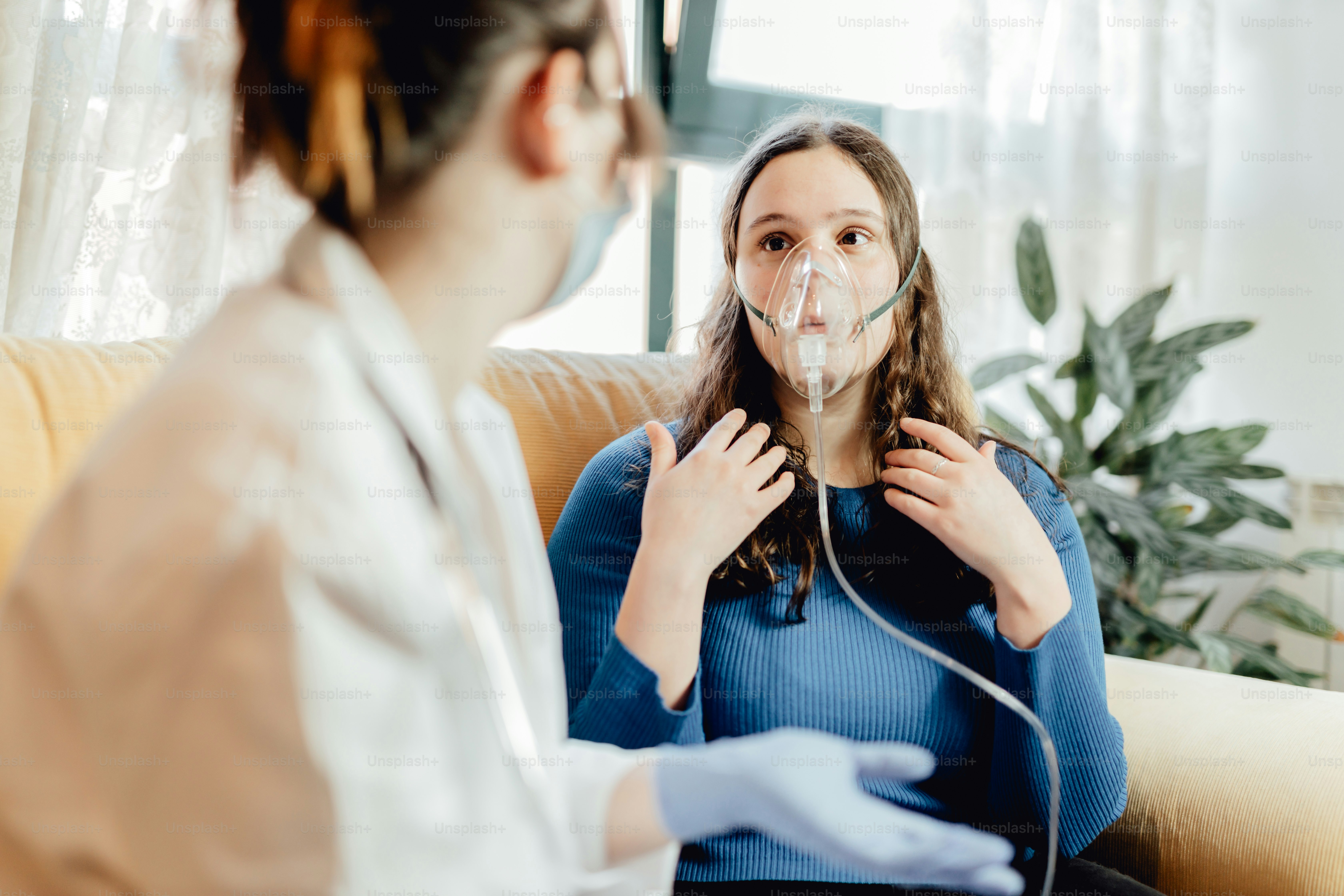 Eine Frau im blauen Pullover hört einer Krankenschwester zu