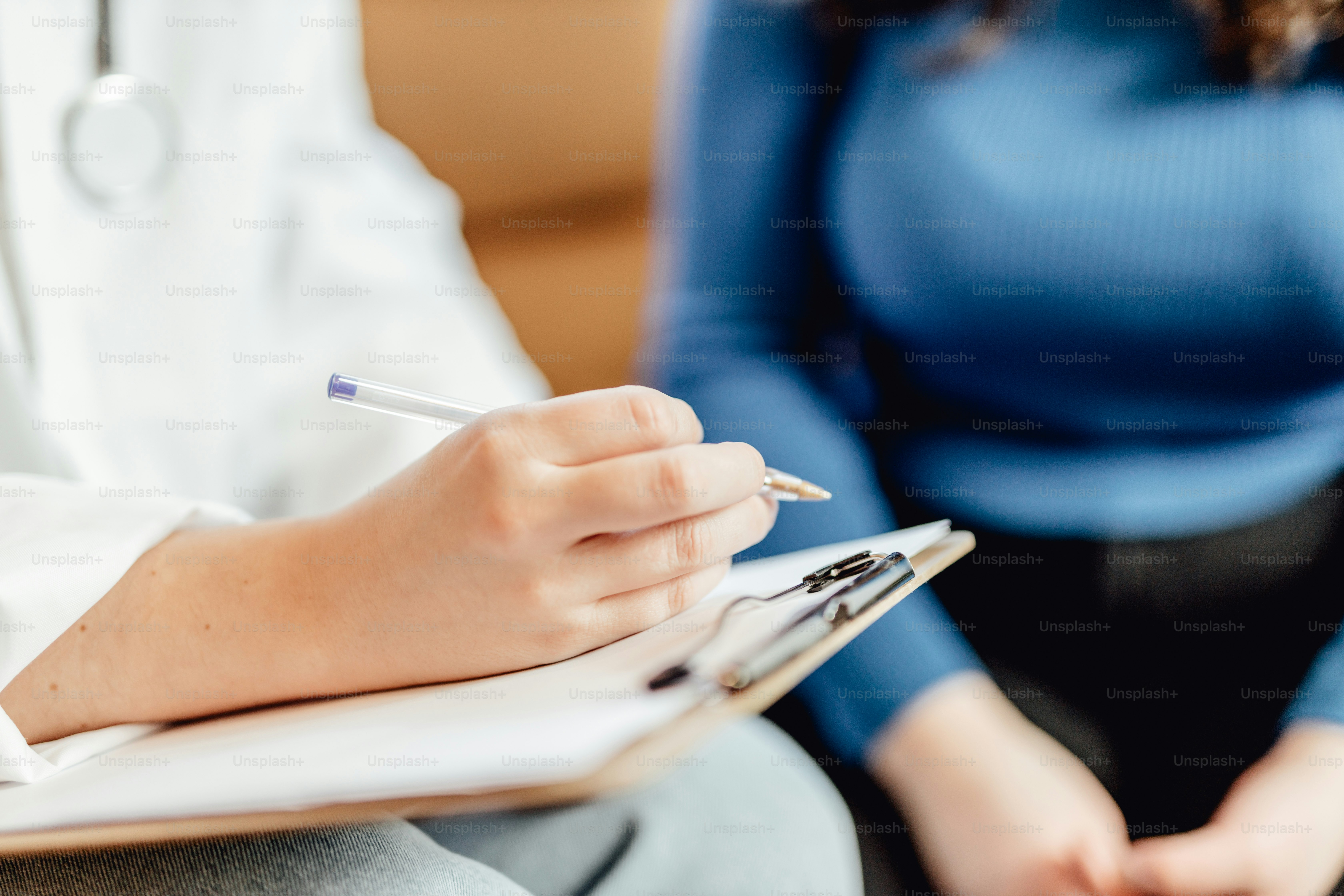 Una mujer con una bata blanca escribiendo en un cuaderno