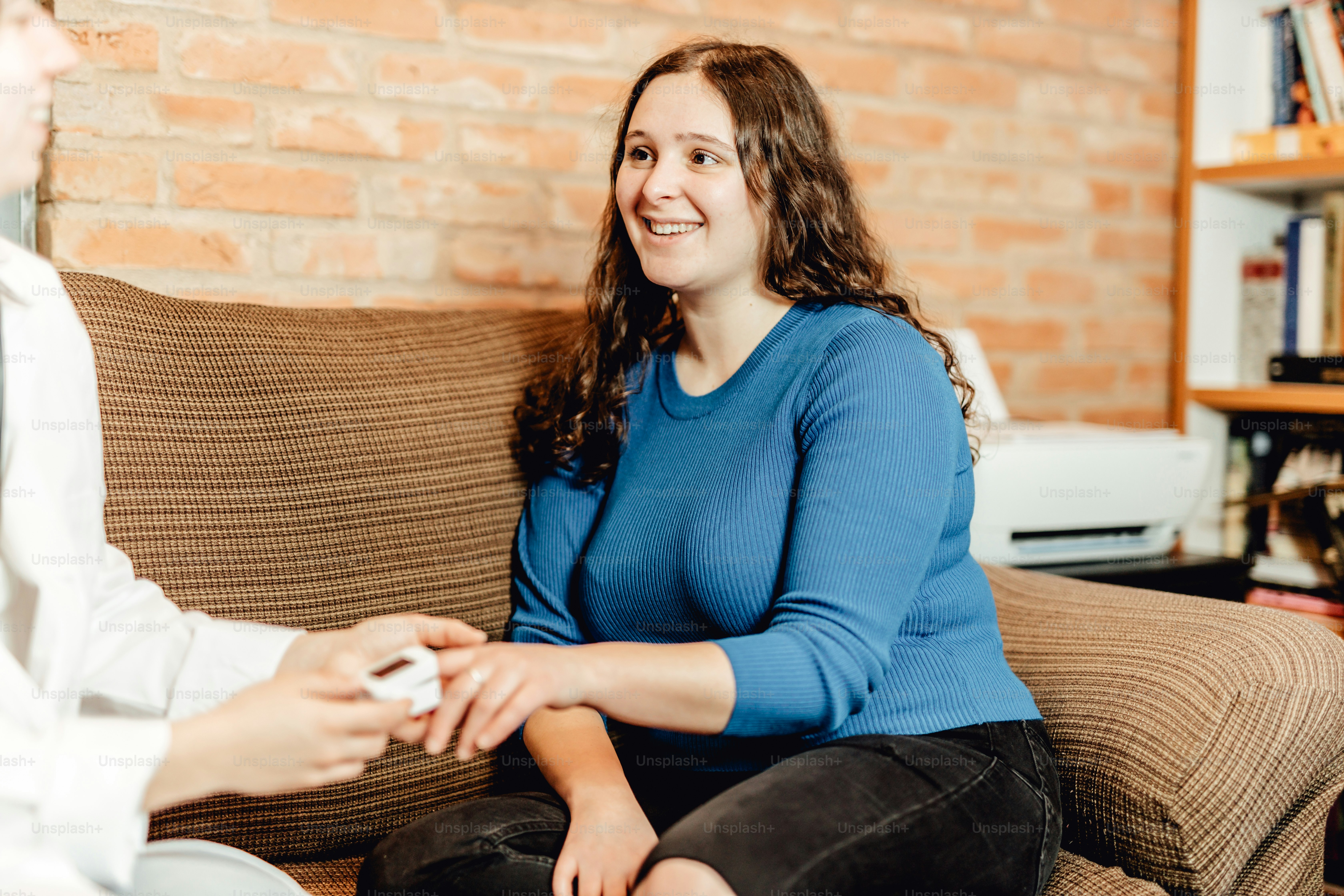 Una mujer sentada en un sofá sosteniendo un control remoto