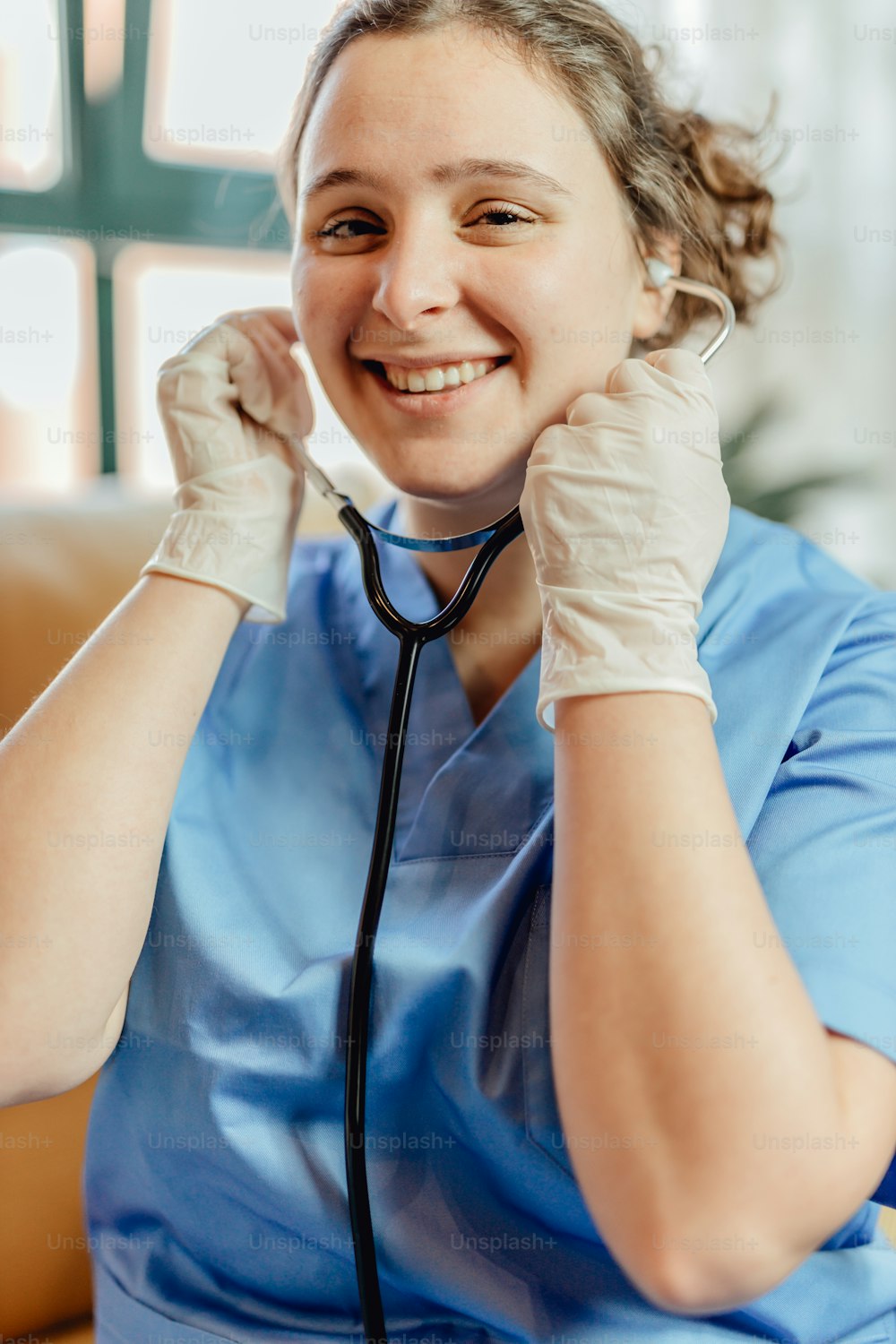 a woman in scrubs and a stethoscope is smiling