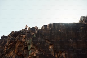 Un uomo in piedi sulla cima di una scogliera rocciosa