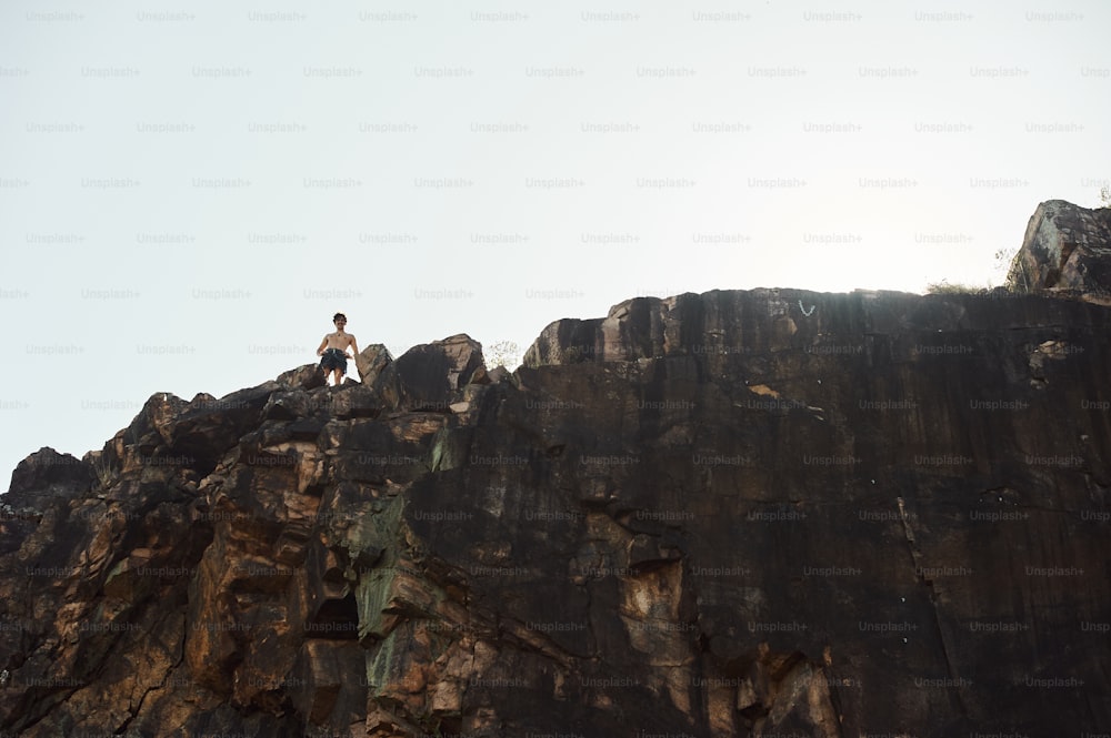 Un homme debout au sommet d’une falaise rocheuse