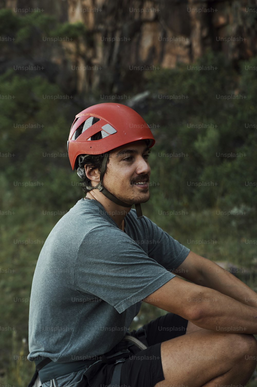 a man wearing a helmet sitting on a rock