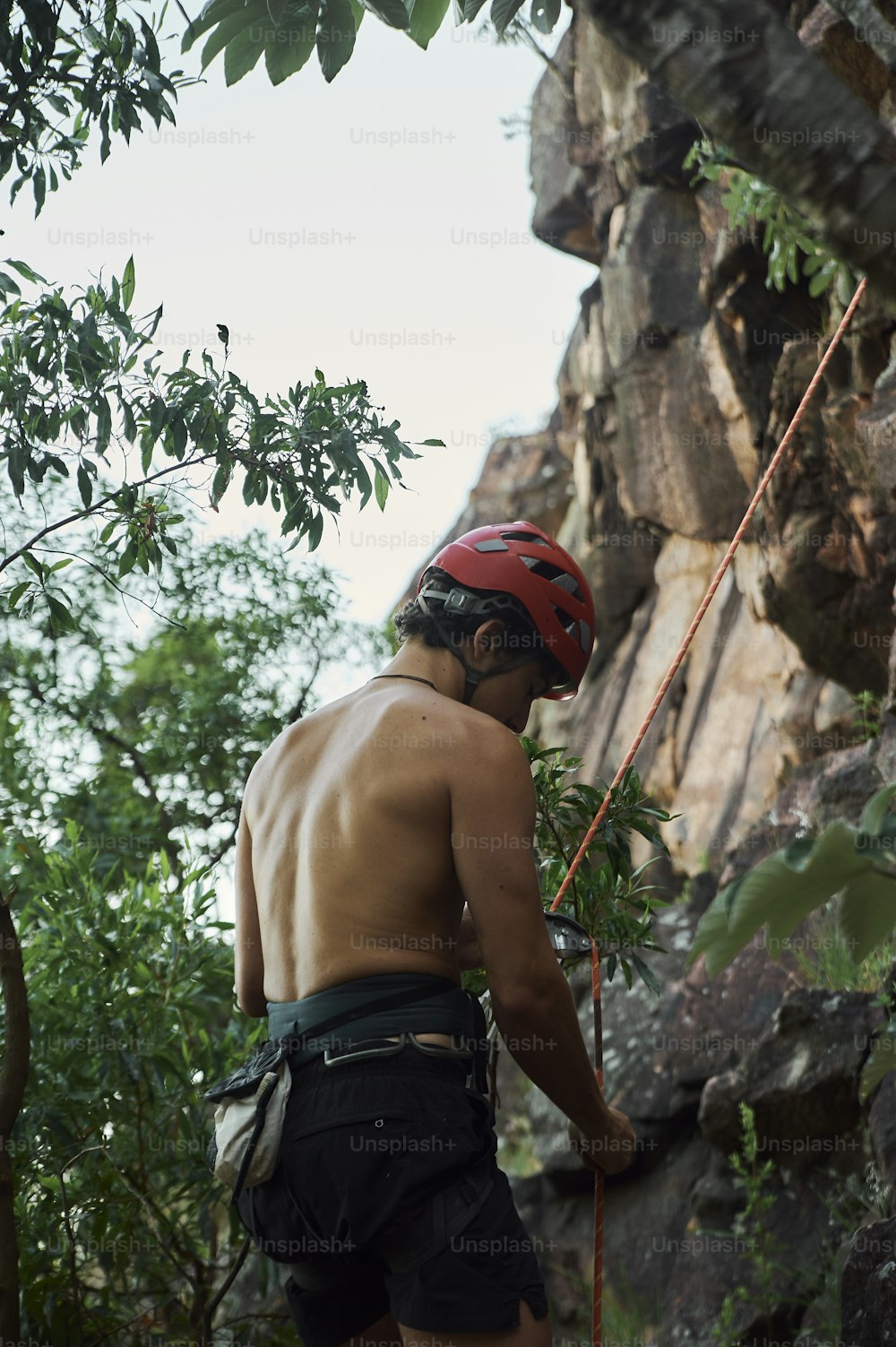 a shirtless man climbing up the side of a mountain