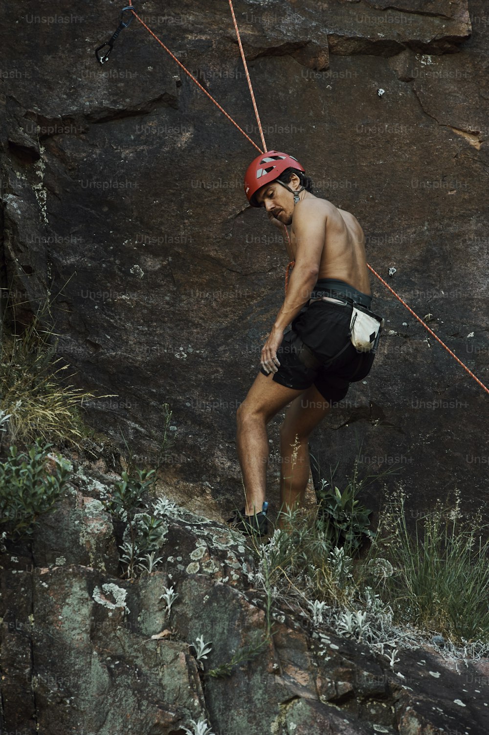 a man with a red helmet is climbing up a mountain