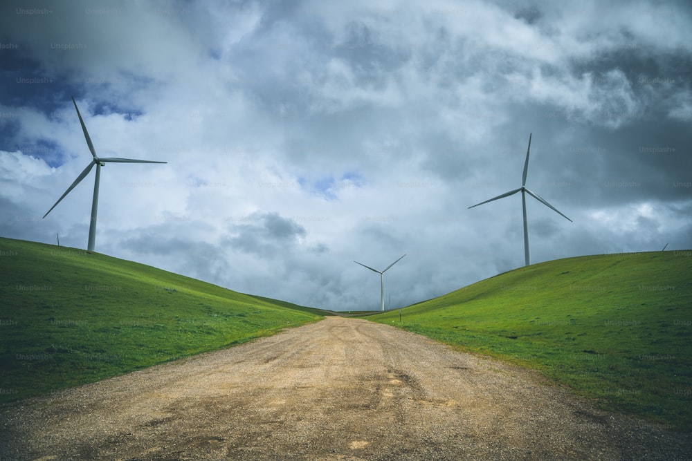 a dirt road with wind turbines in the background