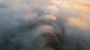 an aerial view of a wind turbine surrounded by clouds